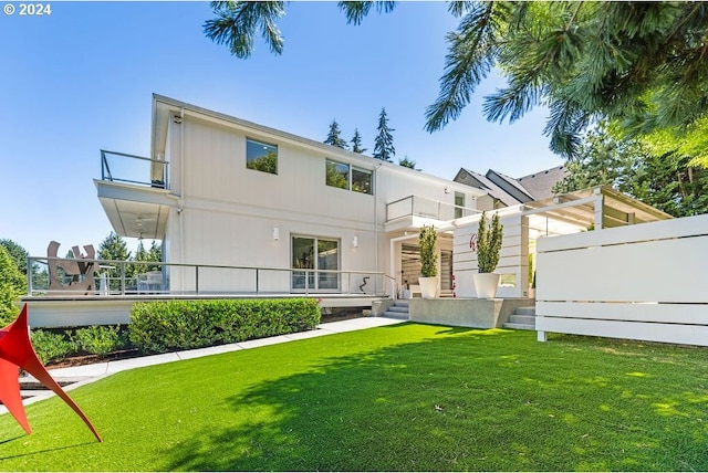 rear view of house featuring a lawn and a balcony