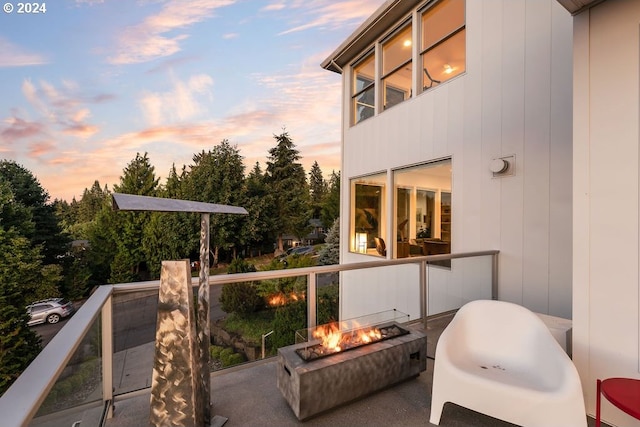 balcony at dusk featuring a fire pit