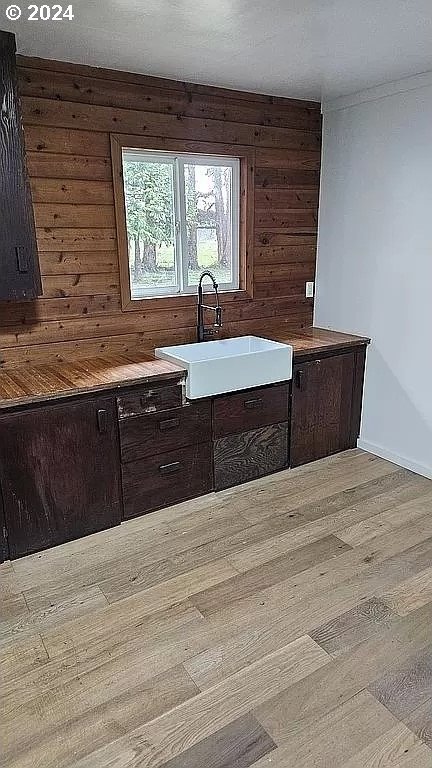 43460 Nicholson Dr, Port Orford, OR 97465 - kitchen with a sink, wood finished floors, wooden walls, and baseboards