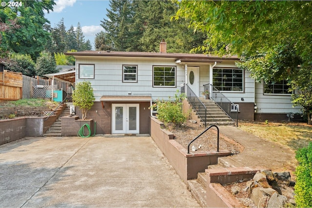 ranch-style home with a chimney, driveway, a patio, french doors, and stairs