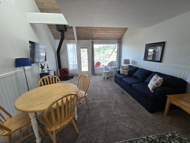 carpeted dining room featuring a wood stove, lofted ceiling, and wood ceiling