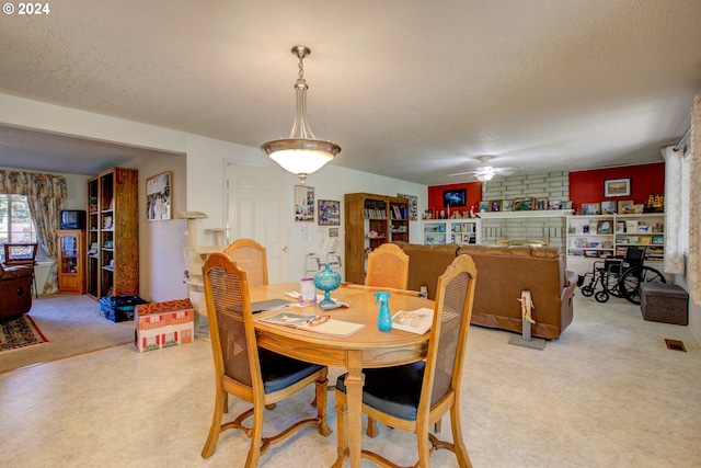 carpeted dining room with a textured ceiling and ceiling fan