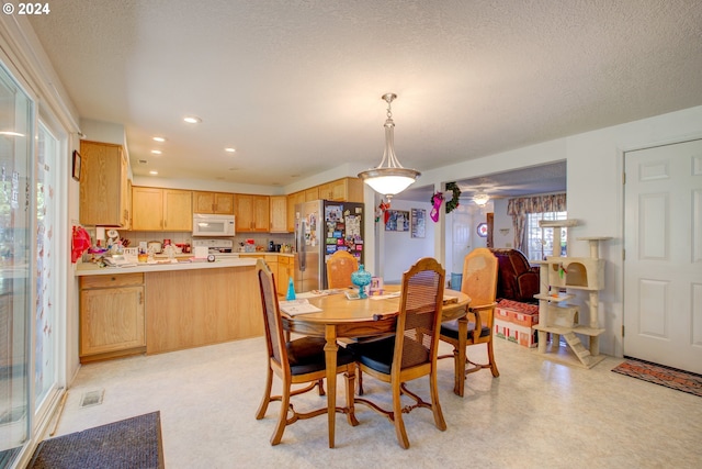 dining space featuring ceiling fan and a textured ceiling