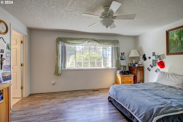 bedroom with a textured ceiling, light wood-type flooring, and ceiling fan