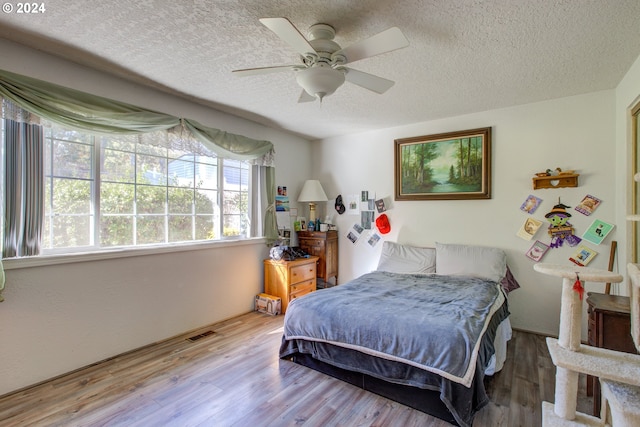 bedroom with ceiling fan, a textured ceiling, and light wood-type flooring