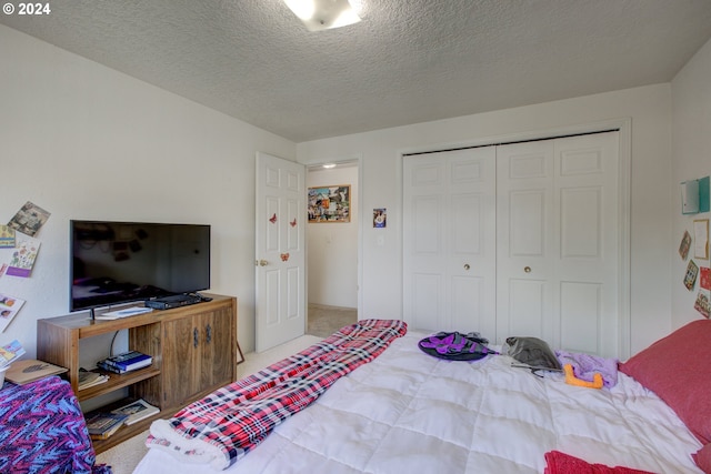 carpeted bedroom featuring a textured ceiling and a closet