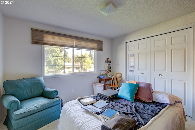 carpeted bedroom featuring a textured ceiling and a closet