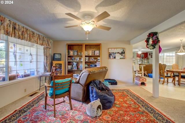 sitting room featuring a textured ceiling, light colored carpet, and ceiling fan