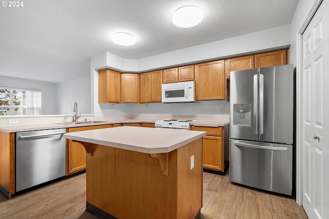 kitchen with sink, light hardwood / wood-style flooring, a textured ceiling, a kitchen island, and stainless steel appliances