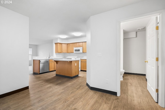 kitchen featuring sink, a kitchen island, white appliances, and hardwood / wood-style flooring