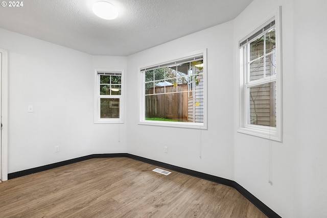 spare room with a textured ceiling and light hardwood / wood-style flooring