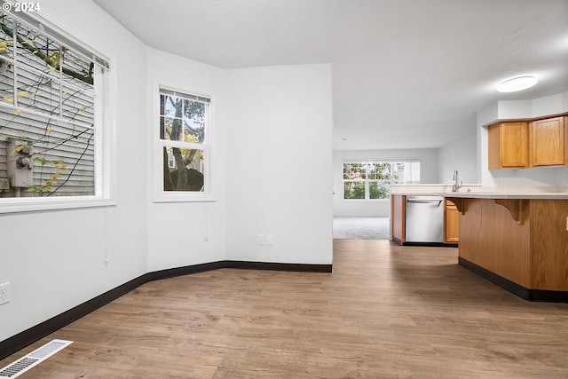 kitchen featuring kitchen peninsula, hardwood / wood-style floors, a kitchen bar, and dishwasher