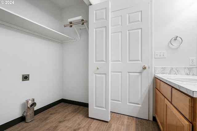 washroom featuring electric dryer hookup, sink, and light hardwood / wood-style flooring