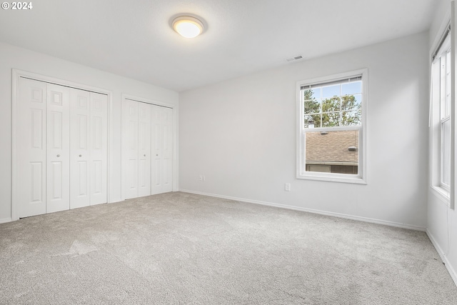 unfurnished bedroom with carpet flooring and two closets