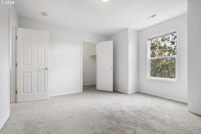 unfurnished bedroom with a spacious closet, a closet, and carpet floors