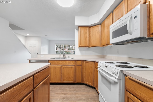 kitchen with a textured ceiling, light hardwood / wood-style floors, white appliances, and sink