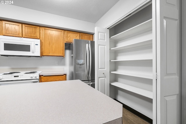 kitchen featuring dark hardwood / wood-style floors, white appliances, and a textured ceiling