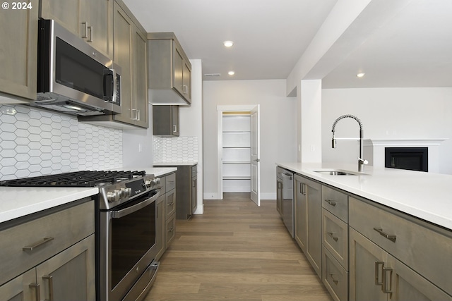 kitchen featuring sink, backsplash, light hardwood / wood-style flooring, and stainless steel appliances