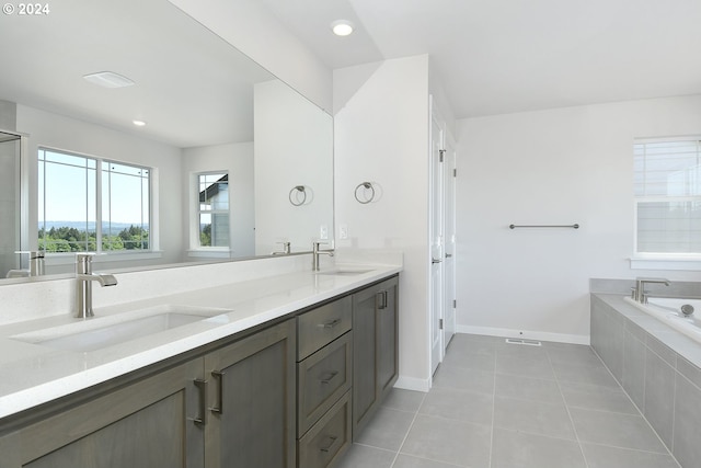 bathroom featuring tiled bath, vanity with extensive cabinet space, dual sinks, and tile flooring