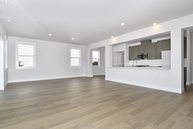 unfurnished living room featuring sink and light hardwood / wood-style flooring