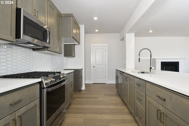 kitchen featuring backsplash, appliances with stainless steel finishes, sink, and hardwood / wood-style floors