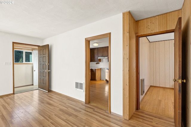 unfurnished bedroom featuring light wood-type flooring, wood walls, and baseboards