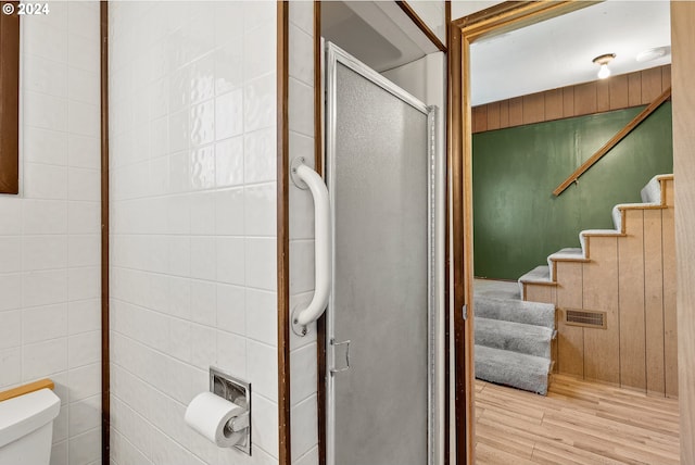 bathroom with wood finished floors, a shower stall, and toilet