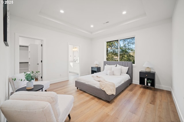 bedroom featuring hardwood / wood-style flooring, a spacious closet, and a tray ceiling