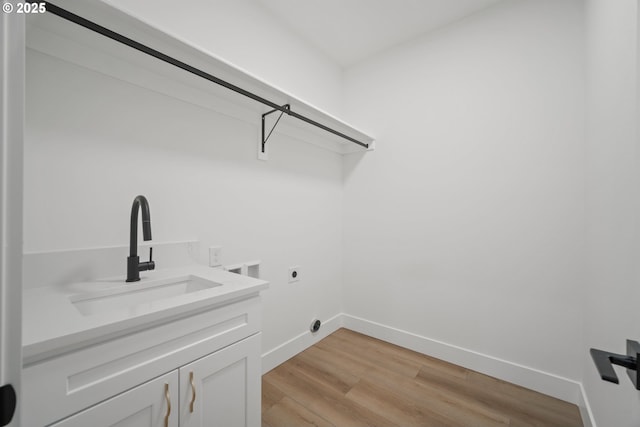 laundry room featuring sink, light hardwood / wood-style flooring, electric dryer hookup, hookup for a washing machine, and cabinets