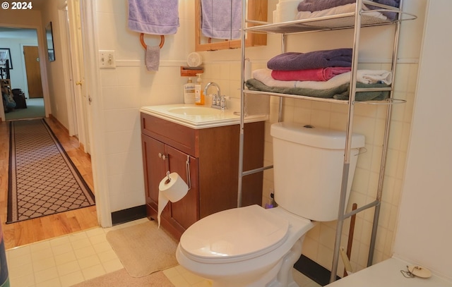 bathroom featuring hardwood / wood-style flooring, vanity, tile walls, and toilet