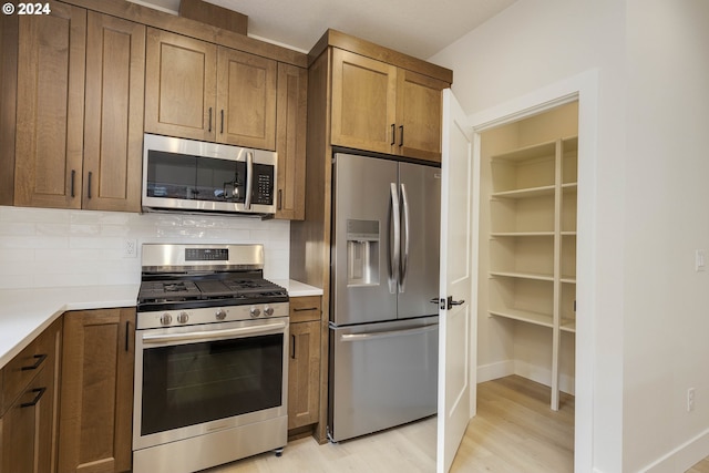 kitchen with stainless steel appliances, backsplash, and light hardwood / wood-style flooring