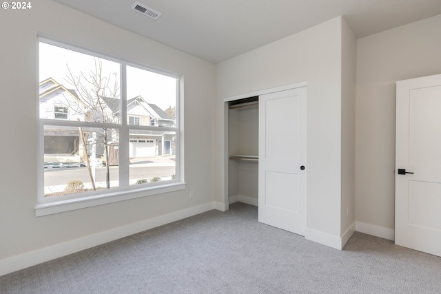 unfurnished bedroom with a closet and light colored carpet