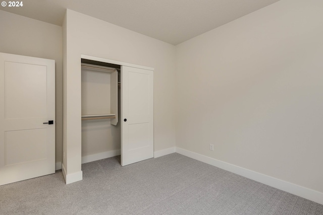 unfurnished bedroom featuring light colored carpet and a closet