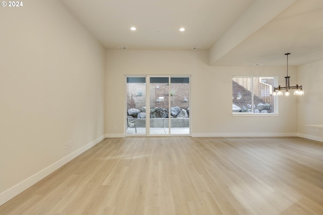 spare room featuring light wood-type flooring and a notable chandelier