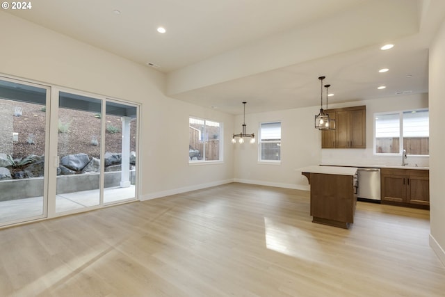 kitchen with a kitchen island, light wood-type flooring, hanging light fixtures, sink, and stainless steel dishwasher