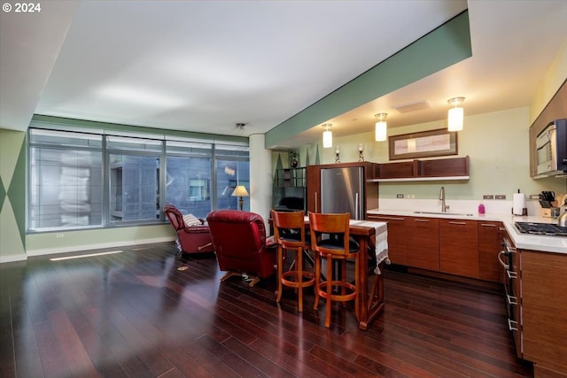 kitchen featuring stainless steel appliances, dark wood-type flooring, light countertops, and a sink