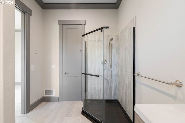 bathroom with crown molding and a shower with shower door