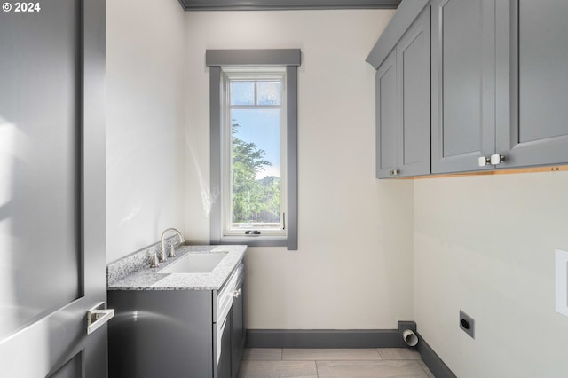 clothes washing area with cabinets, electric dryer hookup, and sink