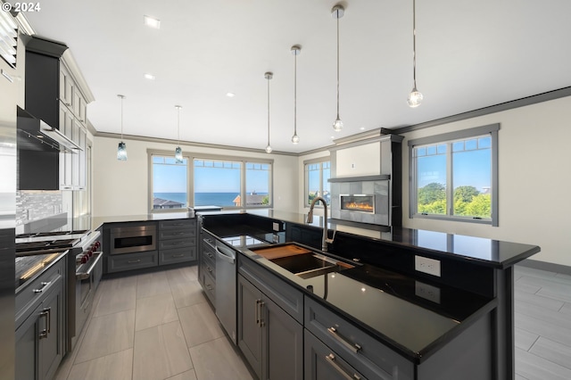 kitchen featuring stainless steel appliances, hanging light fixtures, sink, a water view, and a spacious island