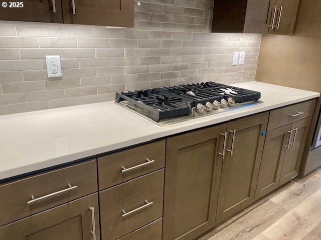 kitchen with tasteful backsplash, light hardwood / wood-style floors, and stainless steel gas stovetop