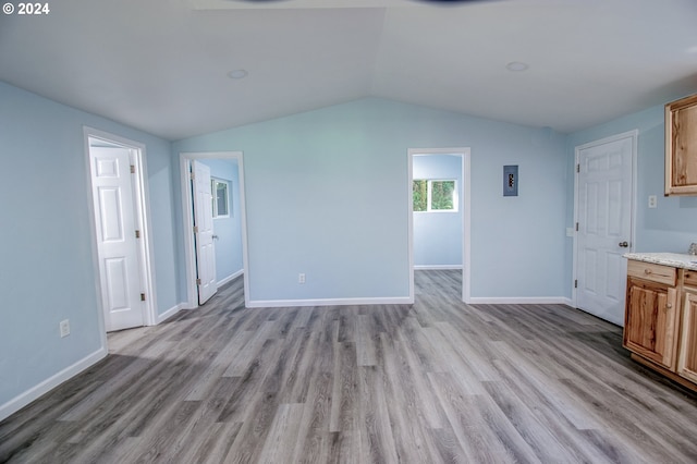 unfurnished living room with lofted ceiling, light hardwood / wood-style flooring, and electric panel