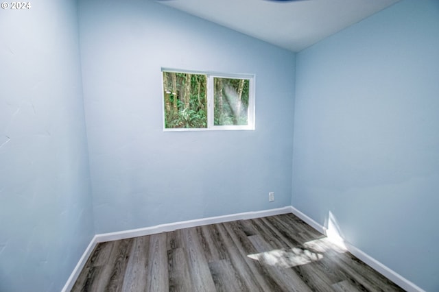 unfurnished room with hardwood / wood-style flooring and vaulted ceiling