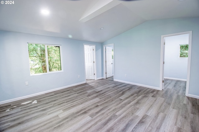 empty room with vaulted ceiling and light hardwood / wood-style flooring