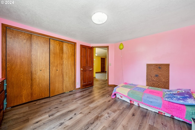 bedroom with a textured ceiling, a closet, and light hardwood / wood-style flooring