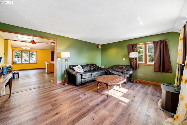 living room featuring a textured ceiling, hardwood / wood-style flooring, vaulted ceiling, and an inviting chandelier