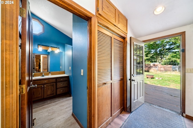 interior space with light hardwood / wood-style floors, sink, and vaulted ceiling