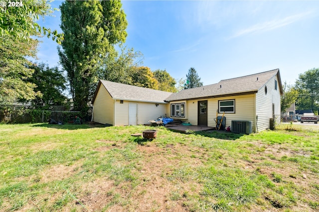 rear view of property featuring central AC unit, a fire pit, a lawn, and a patio