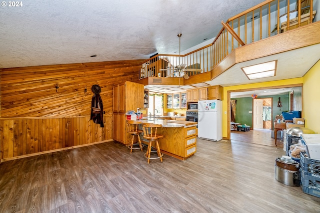 kitchen featuring kitchen peninsula, a textured ceiling, white fridge, and light hardwood / wood-style flooring