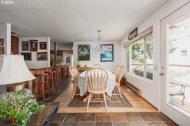 dining space featuring a chandelier, a textured ceiling, dark hardwood / wood-style floors, and baseboard heating