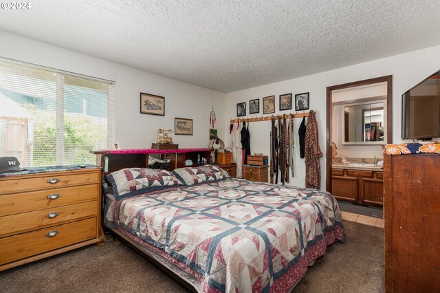 carpeted bedroom with ensuite bath and a textured ceiling